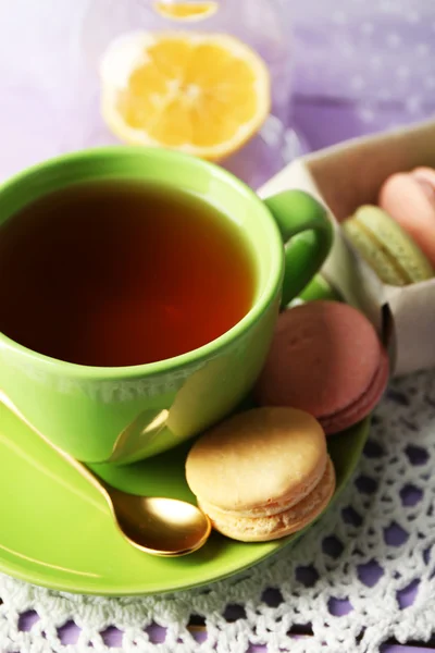 Macaroni colorati con tazza di tè su sfondo di legno — Foto Stock