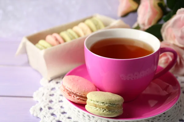 Bunte Makronen mit Tasse Tee auf hölzernem Hintergrund — Stockfoto