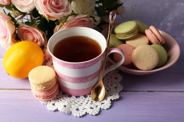 Kleurrijke bitterkoekjes met kopje thee op houten achtergrond — Stockfoto