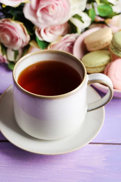 Cup of tea with colorful macaroons on color wooden background — Stock Photo, Image