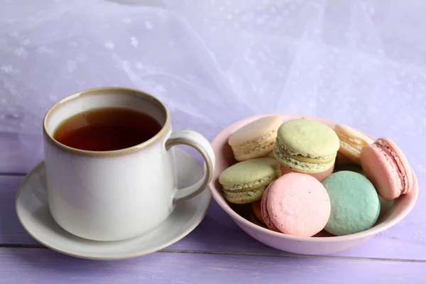 Kopp te med färgglada macaroons på färg trä bakgrund — Stockfoto