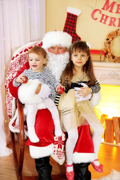 Santa Claus con dos niñas lindas cerca de la chimenea y el árbol de Navidad en casa — Foto de Stock