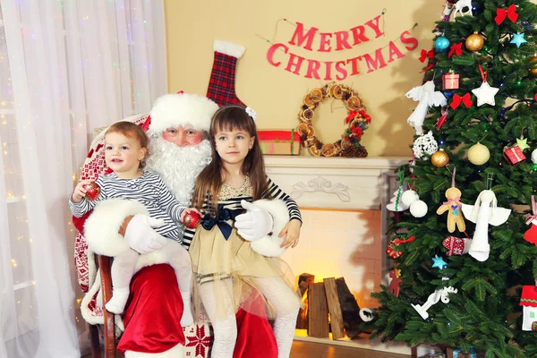Άγιος Βασίλης με δύο μικρά χαριτωμένα κορίτσια κοντά στο τζάκι και το χριστουγεννιάτικο δέντρο στο σπίτι — Φωτογραφία Αρχείου