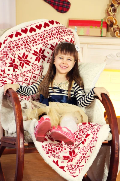 Little girl sitting in rocking chair near fireplace — Stock Photo, Image