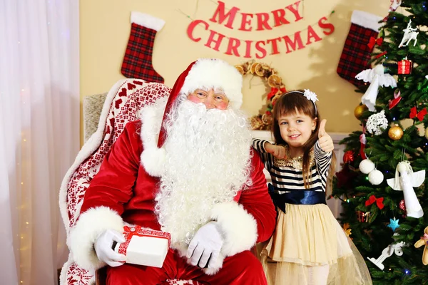 Santa Claus giving  present to  little cute girl near Christmas tree at home — Stock Photo, Image