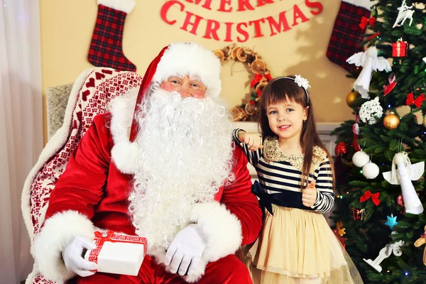 Santa Claus giving  present to  little cute girl near Christmas tree at home — Stock Photo, Image