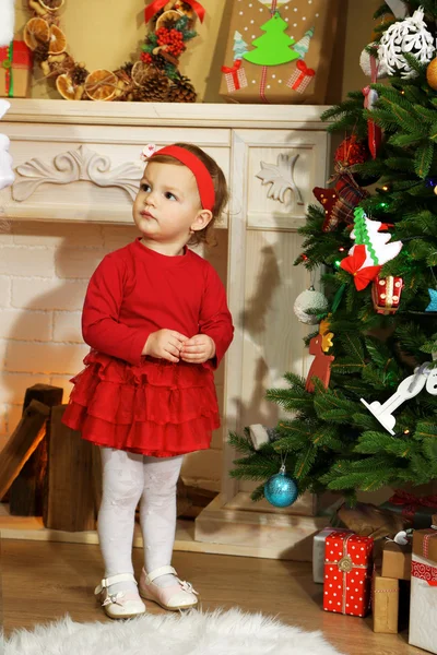 Little girl near fireplace  and Christmas tree Stock Picture