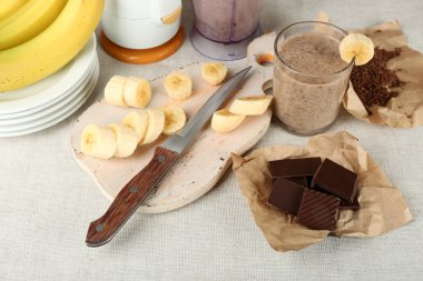 Ahşap arka plan üzerinde muz kesme tahtası ve kıyılmış çikolata, dilimlenmiş