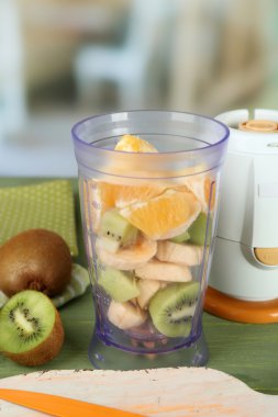 Dilimlenmiş meyve ve blender parlak zemin üzerine ahşap tablo