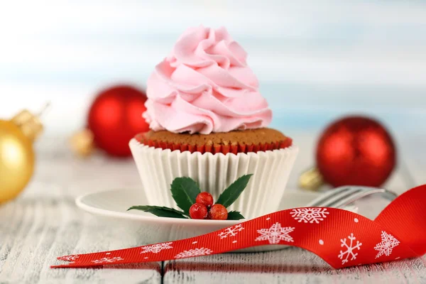 Cup-cake on saucer with Christmas decoration on wooden table and light background — Stock Photo, Image