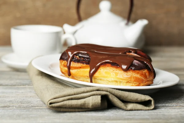 Des éclairs savoureux et une tasse de thé sur une table en bois — Photo