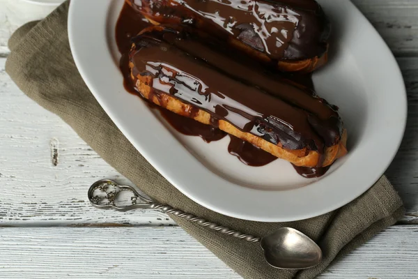 Tasty eclairs on wooden table, close up — Stock Photo, Image