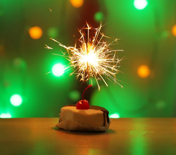 Tasty cake with sparkler on shiny background — Stock Photo, Image