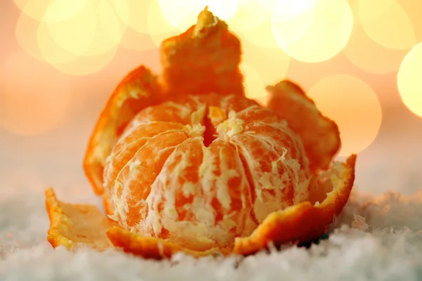 Свежий спелый мандарин на снегу, на фоне огней — стоковое фото
