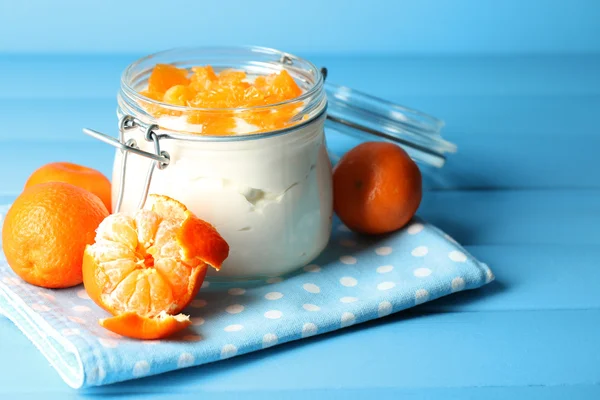 Ízletes tejet desszert a friss mandarin darabokat üvegedénybe, színes fából készült háttér — Stock Fotó