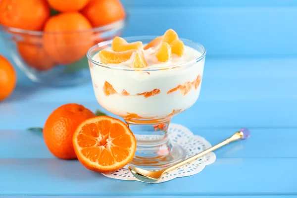 Ízletes tejet desszert a friss mandarin darabokat üvegtál, színes fából készült háttér — Stock Fotó