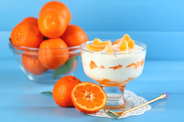 Sabroso postre de leche con trozos de mandarina fresca en tazón de vidrio, sobre fondo de madera de color —  Fotos de Stock