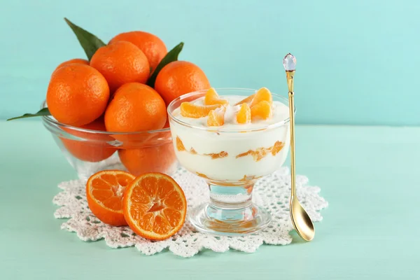 Gustoso dessert al latte con pezzi di mandarino fresco in barattolo di vetro e palline di Natale, su sfondo di legno a colori — Foto Stock