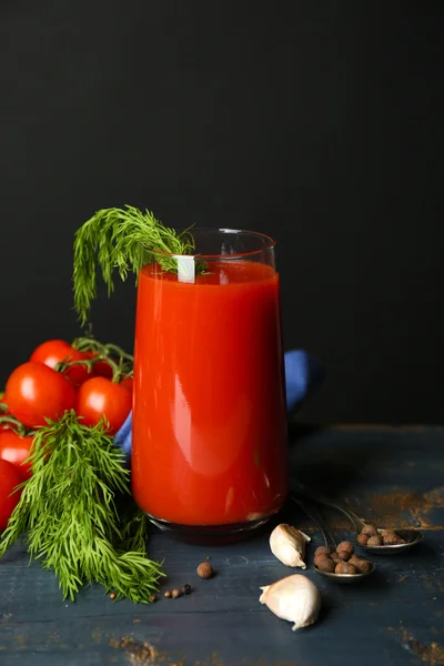 Vaso de sabroso jugo de tomate y tomates frescos sobre la mesa, sobre fondo gris — Foto de Stock