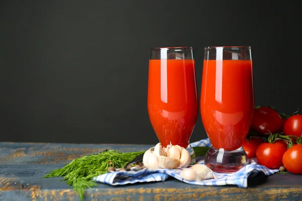美味的番茄汁和新鲜的西红柿在桌子上，在灰色的背景上的眼镜 — 图库照片
