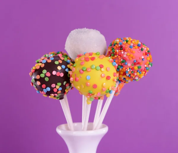 Sweet cake pops in vase on purple background — Stock Photo, Image