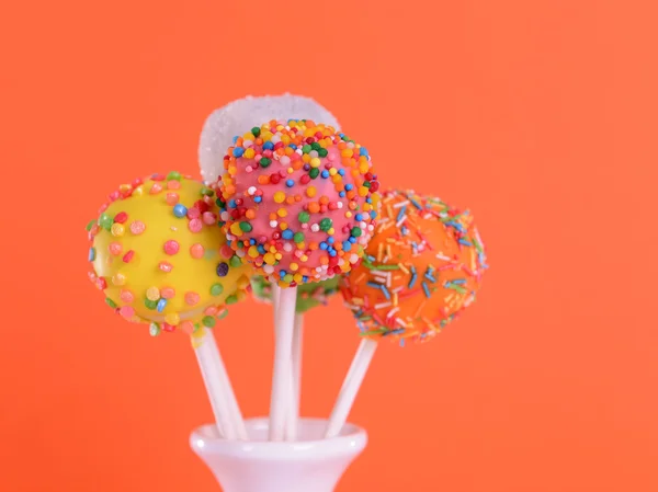 Sweet cake pops in vase on orange background — Stock Photo, Image