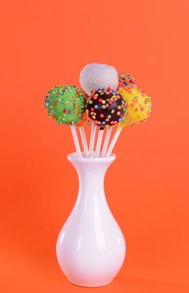 Sweet cake pops in vase on orange background — Stock Photo, Image