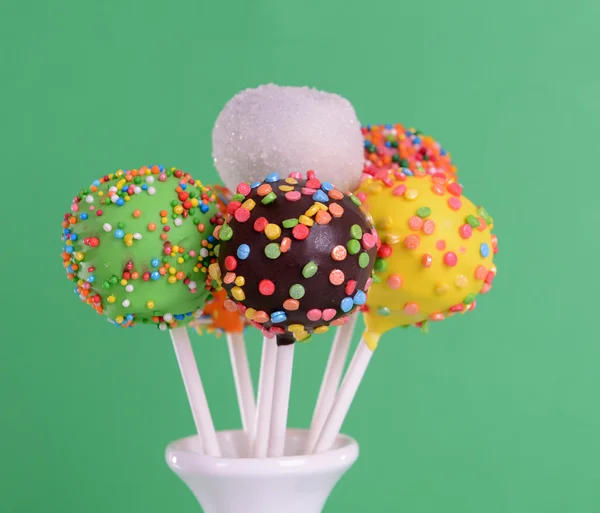 Sweet cake pops in vase on green background — Stock Photo, Image