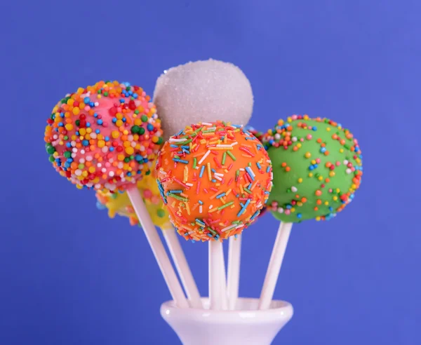 Söta cake pops i vas på blå bakgrund — Stockfoto