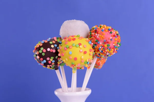 Sweet cake pops in vase on blue background — Stock Photo, Image