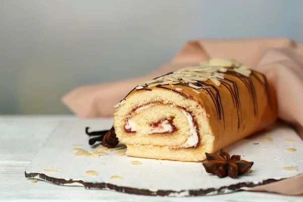 Delicioso pastel de rollo sobre mesa de madera, sobre fondo claro — Foto de Stock