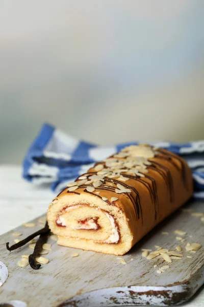 Delicious roll cake on wooden table, on light background — Stock Photo, Image