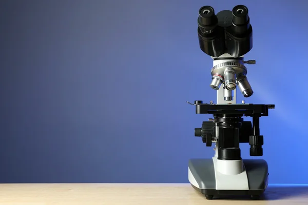 Microscope on table, on color background — Stock Photo, Image