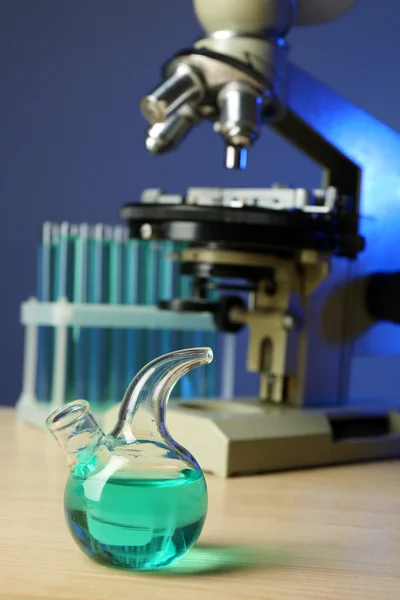 Microscope and test tubes on table, on color background — Stock Photo, Image