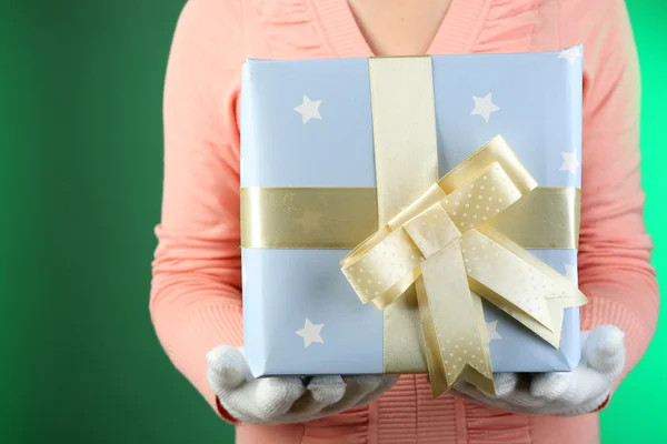 Scatola regalo in mano femminile su sfondo a colori — Foto Stock