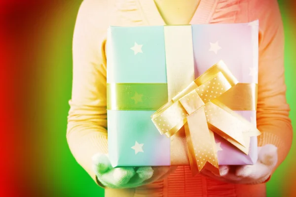 Scatola regalo in mani femminili su sfondo a colori — Foto Stock