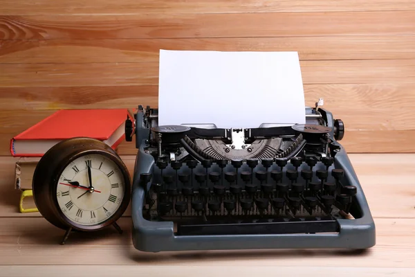 Винтажная пишущая машинка и часы на столе — стоковое фото
