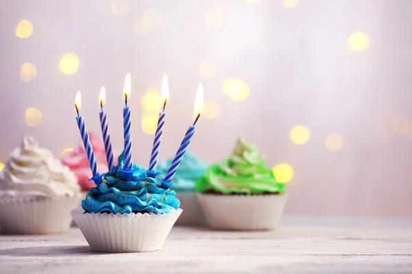 Deliciosos cupcakes de aniversário na mesa no fundo claro — Fotografia de Stock