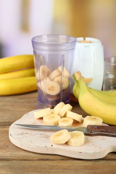Нарезанный банан на разделочной доске, на деревянном столе, на ярком фоне — стоковое фото