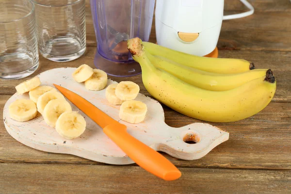 Plasterki banana na deski do krojenia, na tle drewniane — Zdjęcie stockowe