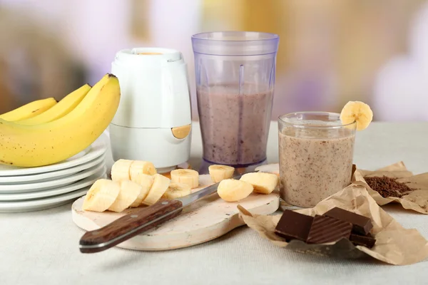 Banana fatiada na tábua de corte e chocolate picado, na mesa de madeira, no fundo brilhante — Fotografia de Stock