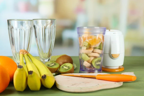 Dilimlenmiş meyve ve blender parlak zemin üzerine ahşap tablo