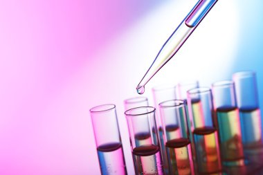 Sıvı test tüpleri arka plan parlak pembe birine ekleyerek pipet