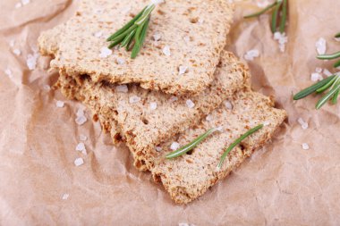 Crispbread tuz, yağ sürahi ve dal biberiye buruşuk kağıt arka plan parçası üzerinde