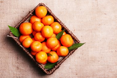 Fresh ripe mandarins in wooden box, on sackcloth background  clipart