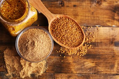 Hardal tohumu, toz ve Cam Kavanoz, kase ve tahta kaşıklar ahşap zemin üzerine sos