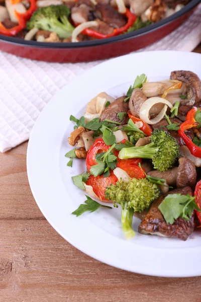 Champiñones silvestres estofados con verduras y especias en sartén y plato sobre mesa — Foto de Stock