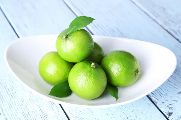 Limas jugosas frescas en plato sobre fondo de madera —  Fotos de Stock