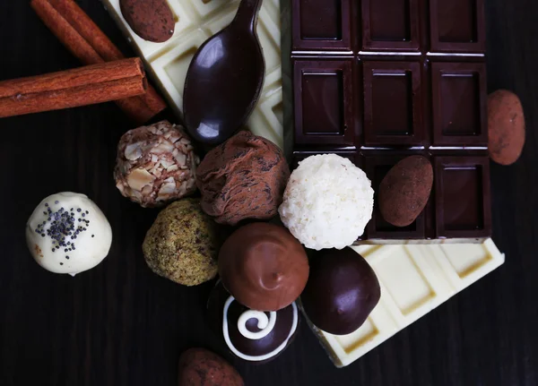 Barrette di cioccolatini bianchi e amari con caramelle e cucchiaio dolce sullo sfondo liscio in legno scuro — Foto Stock