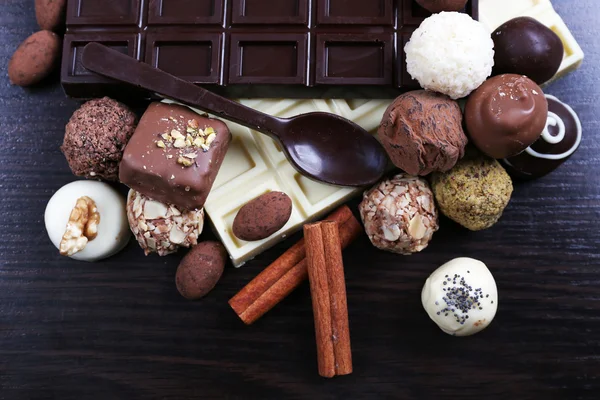 Bares de chocolates brancos e amargos com doces e colher doce no fundo liso de madeira escura — Fotografia de Stock
